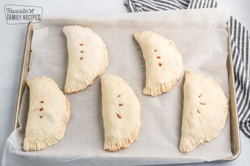 Raw calzones on a baking sheet