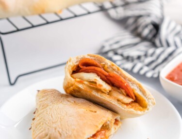 A pepperoni calzone cut in half on a plate