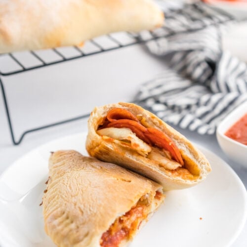 A pepperoni calzone cut in half on a plate