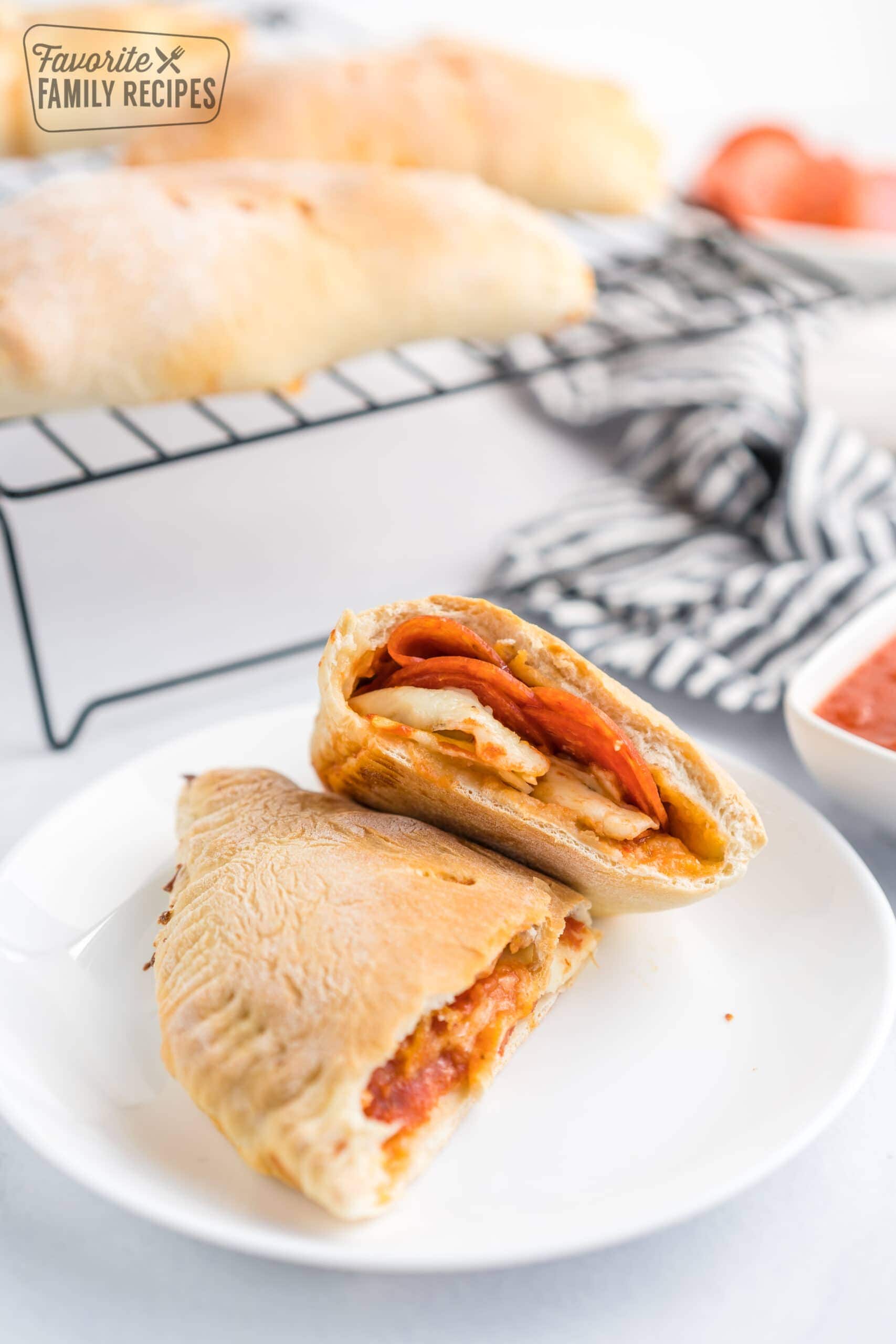 A pepperoni calzone cut in half on a plate.