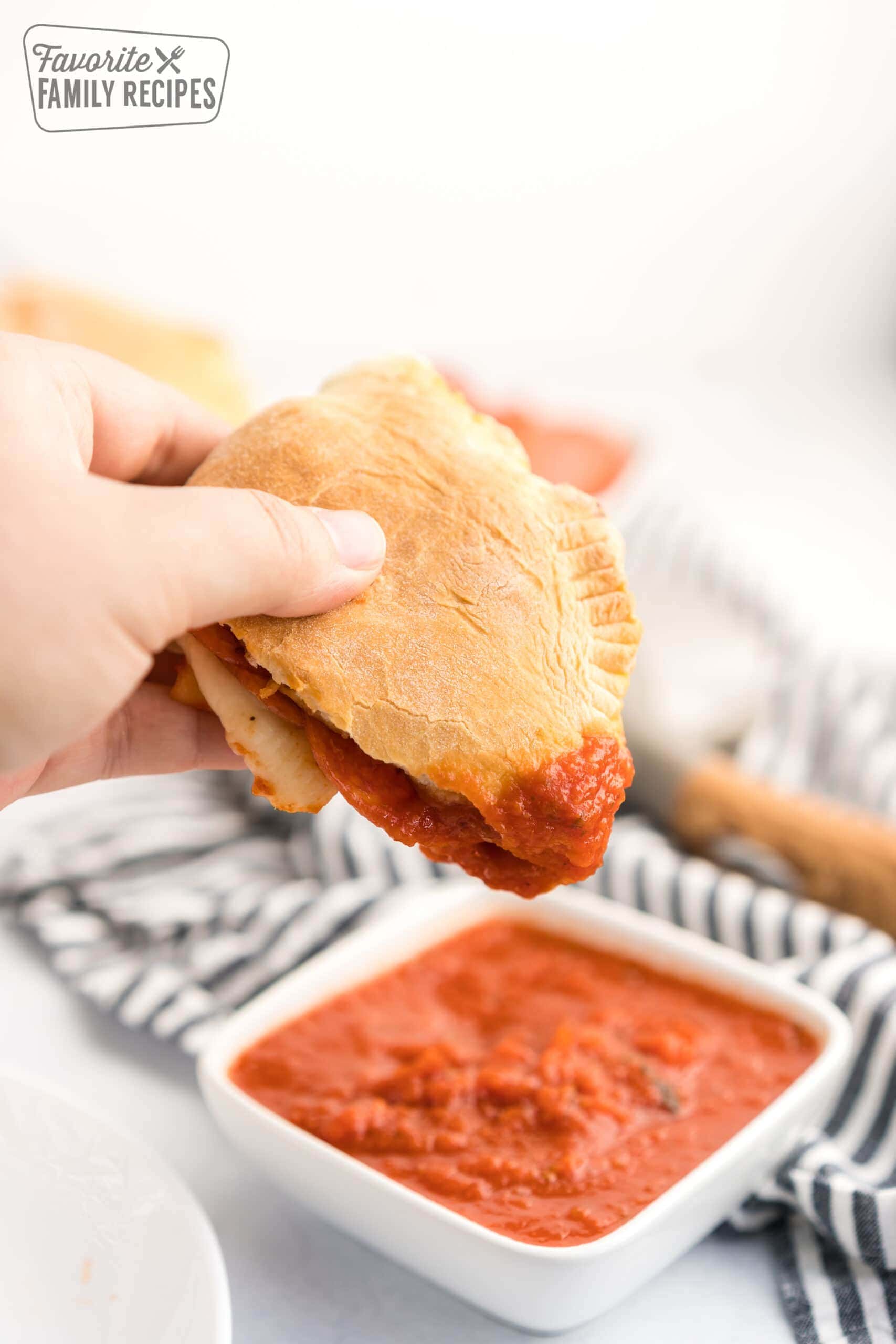A calzone being dipped in marinara sauce