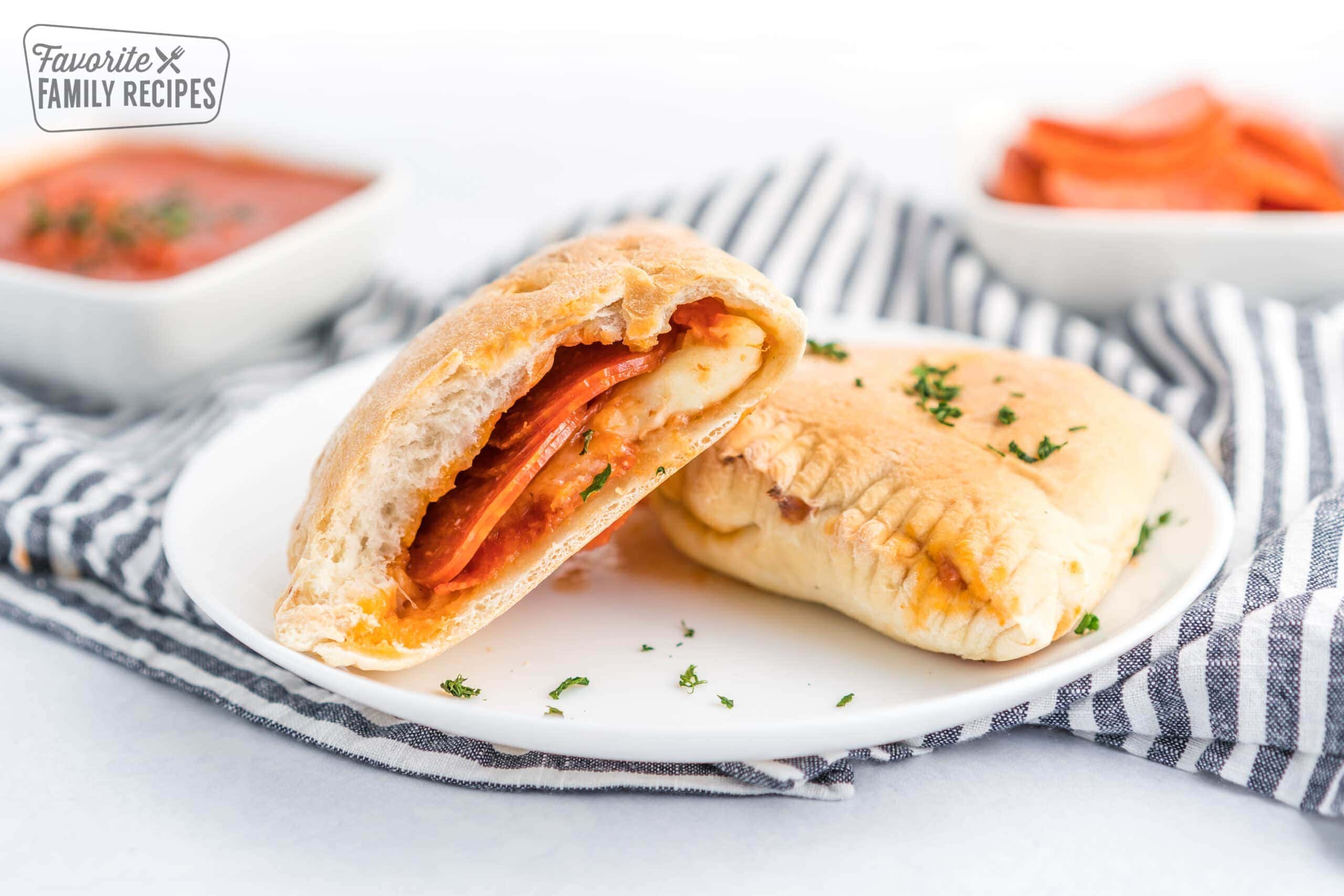 A pepperoni calzone cut in half on a white plate.