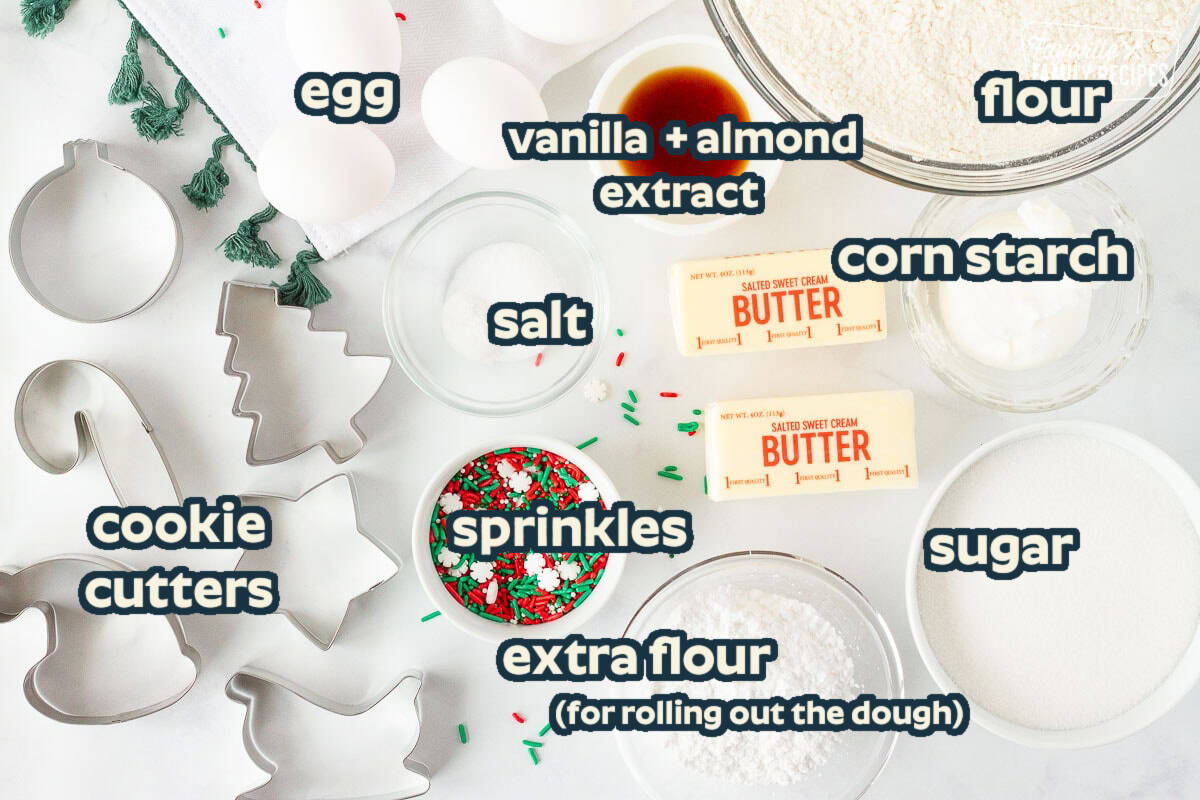 Flour, sugar, butter, crisco, vanilla, eggs, sprinkles, cookie cutters, sprinkles and dry ingredients for Christmas Sugar Cookies.