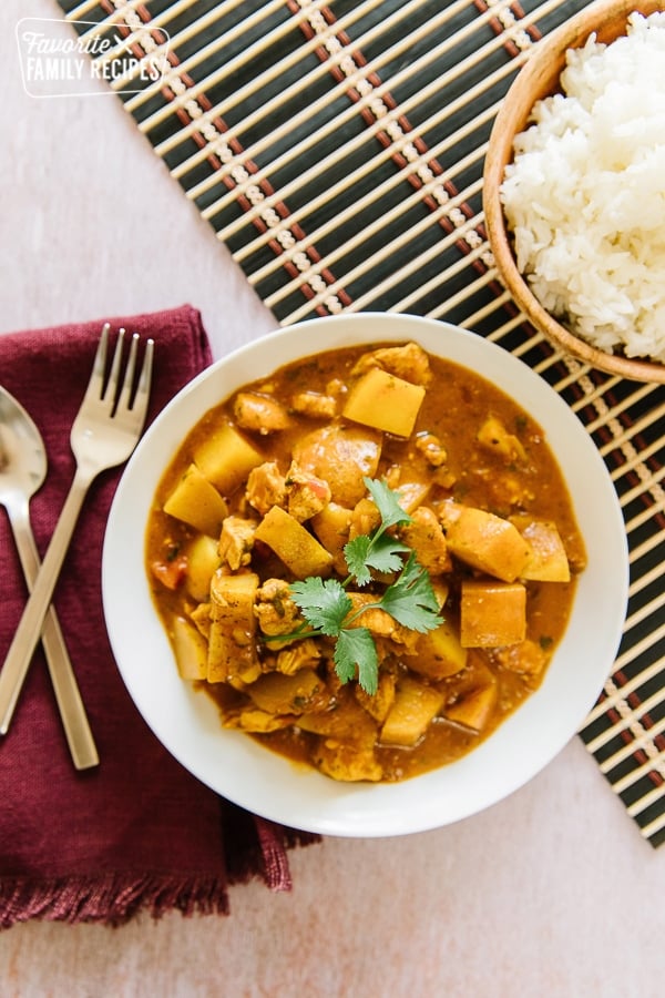 Chicken Coconut Curry is warm, hearty and layered with sweet and savory flavors. Tastes even better than restaurant curries and much cheaper and easier to make! Chicken Coconut Curry in a bowl with a side of rice