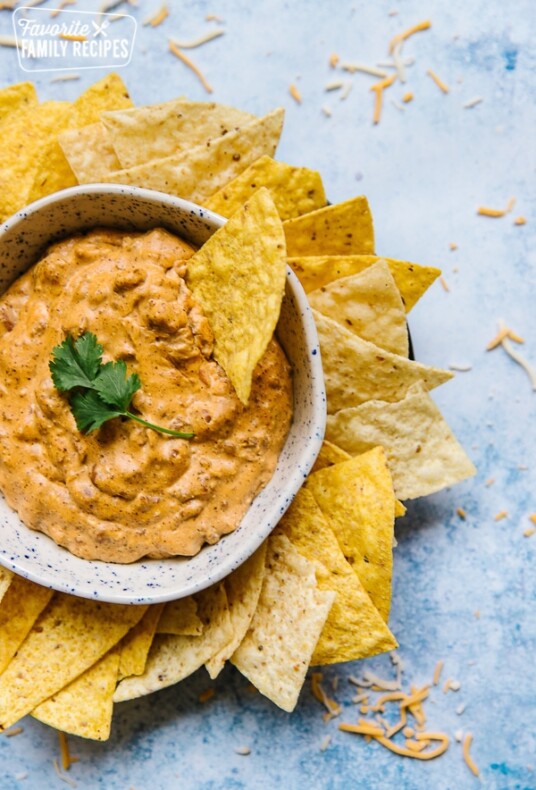 Chili Cheese Dip in a bowl with a sprig of cilantro surrounded by tortilla chips