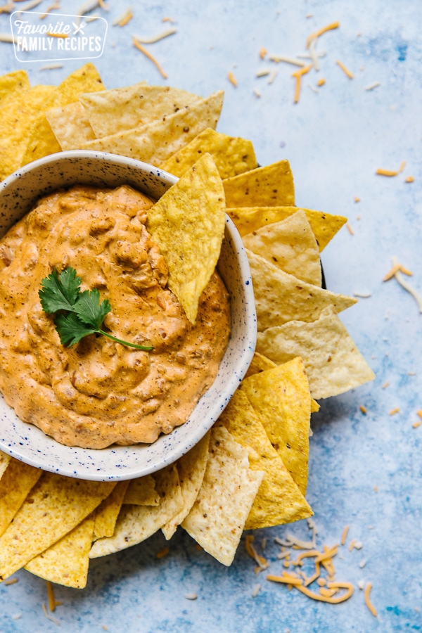 Chili Cheese Dip in a bowl with a sprig of cilantro surrounded by tortilla chips