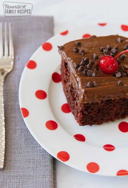 Chocolate Cherry Cake with a cherry on top on a white plate with red polka dots