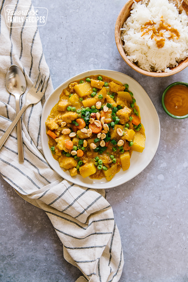 Coconut Curry Chicken plated with a jasmine rice bowl and peanut sauce to the side