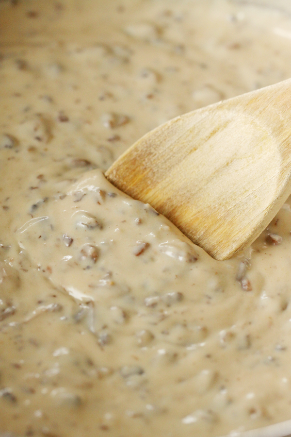 Close up of cream of mushroom soup in a saucepan with wooden spoon