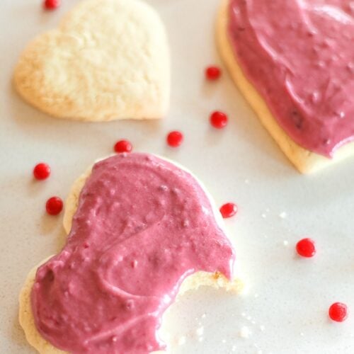 Sugar Cookies with Raspberry Frosting with a bite out of one cookie