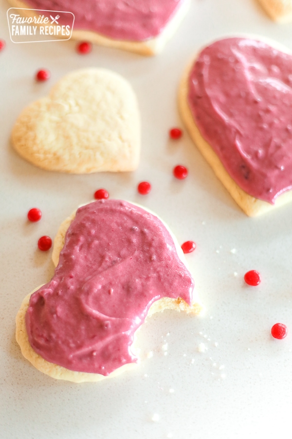 Sugar Cookies with Raspberry Frosting with a bite out of one cookie