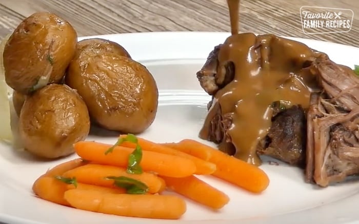 Sunday roast with carrots and potatoes on a white plate.