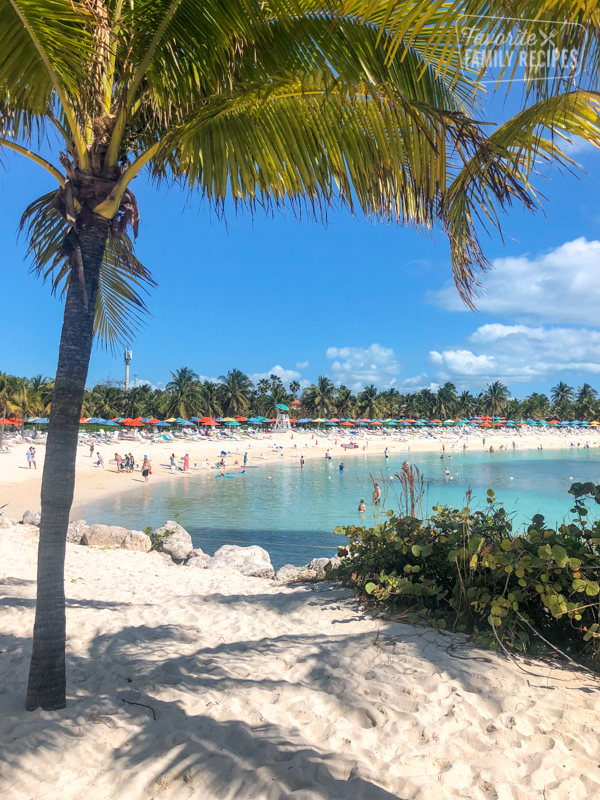 Castaway cay beach with umbrellas and people swimming in the ocean. 