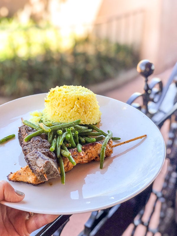 Mix Grill Skewers with marinated beef and chicken served with green beans and rice or roasted potatoes on a plate at Spice Road Table at Epcot's World Showcase