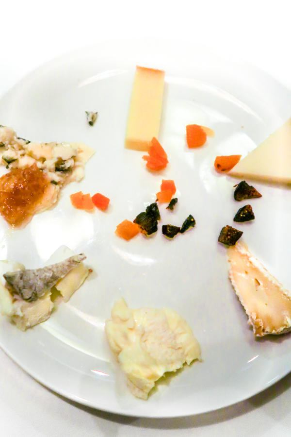 A cheese plate with cheese arranged in a circle, with honeycomb and dried fruits.