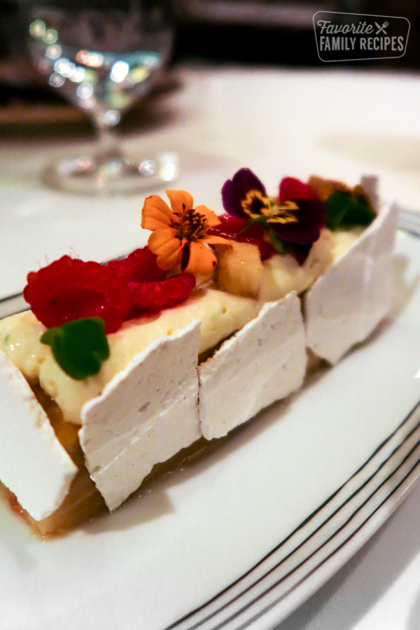 Gluten-free banana cream dessert with raspberries, white chocolate and edible flowers.