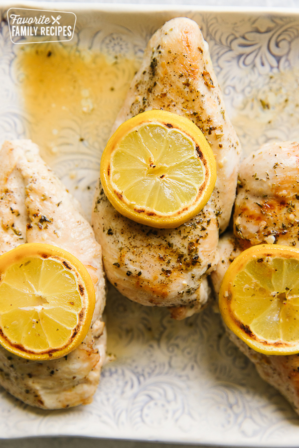Three lemon chicken breasts topped with lemon slices