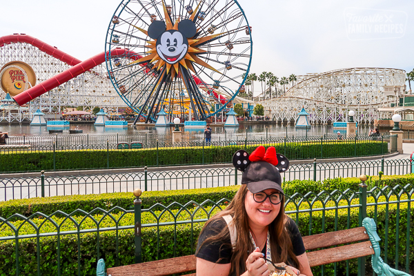 A woman sitting on a bench sampling food from Disney California Adventure Park Food and Wine Festival