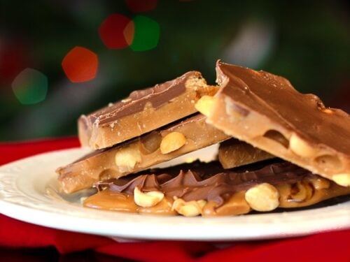 English toffee piled on a white plate with Christmas lights in the background