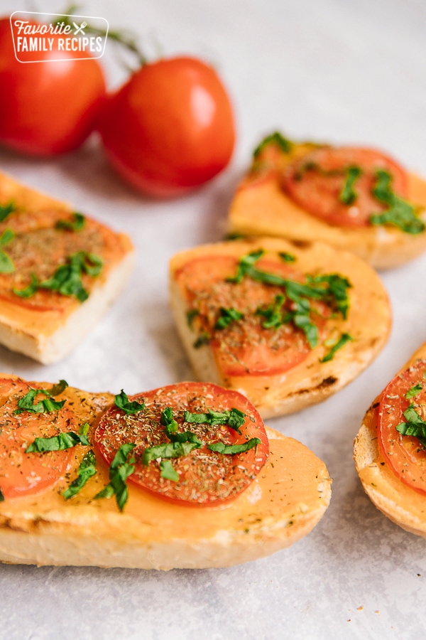 Slices of Cheesy Italian Bread with fresh tomatoes on the side