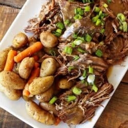 Instant Pot Sunday Beef Roast shredded on a serving plate with potatoes and carrots