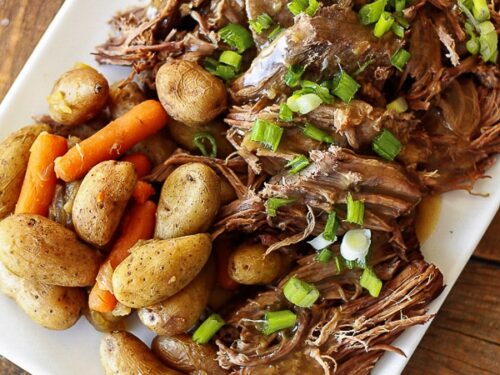 Instant Pot Sunday Beef Roast shredded on a serving plate with potatoes and carrots