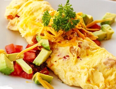 Side view of Omelette in a Bag with tomatoes, avocado, and cheese toppings
