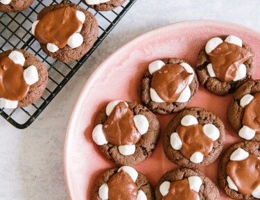 Chocolate marshmallow cookies on a cooling rack with a plate of cookies to the side