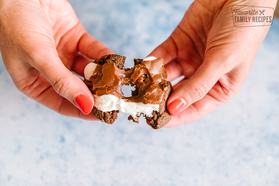 A chocolate marshmallow cookie being pulled apart with gooey marshmallow in the center