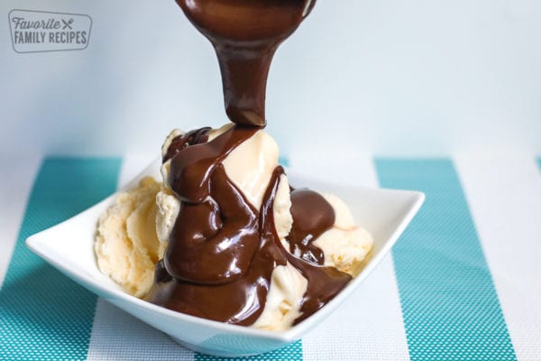 A bowl of vanilla ice cream with hot fudge sauce poured over the top