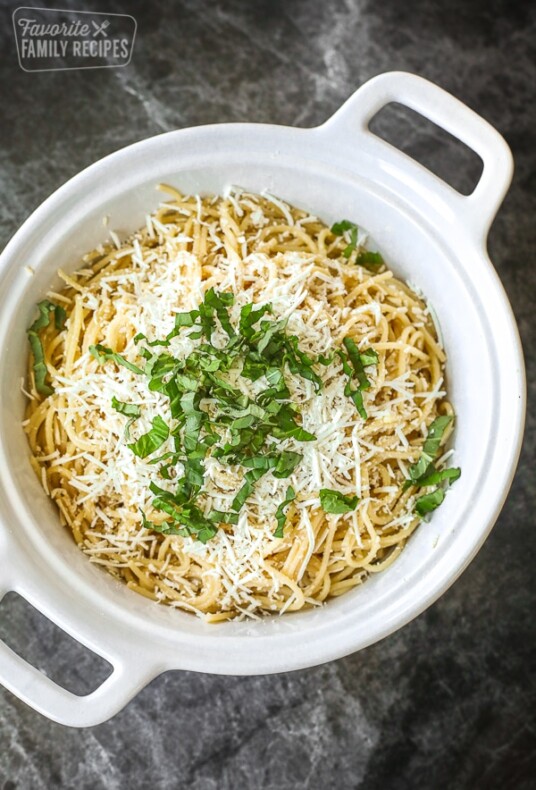A white casserole dish filled with Mizithra Pasta topped with cheese and parsley