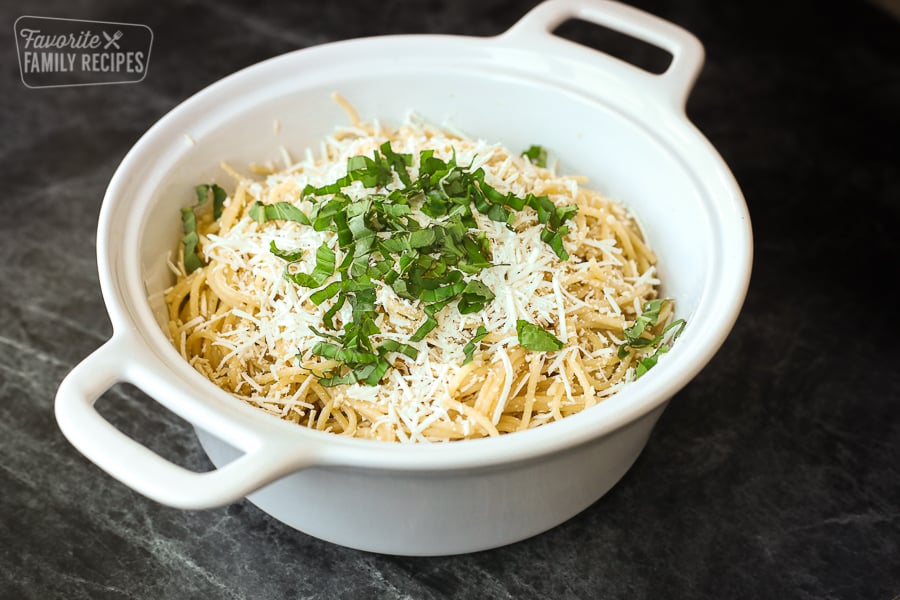 A landscape view of mizithra pasta sprinkled with mizithra cheese and basil on top