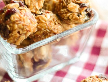 PB & J Energy Bites in a glass square bowl on a checkered table cloth.