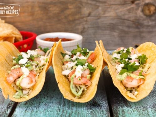 Three shrimp tacos garnished with cotija cheese and cilantro
