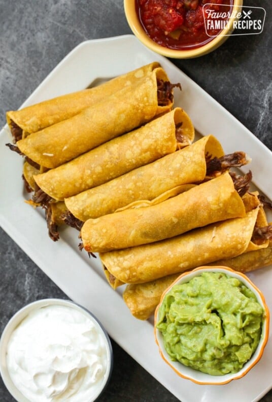 A platter filled with shredded beef taquitos