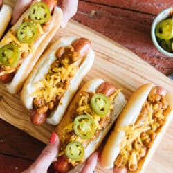 Four Chili Cheese Dogs on a tray with a cup of sliced jalapeños on the side