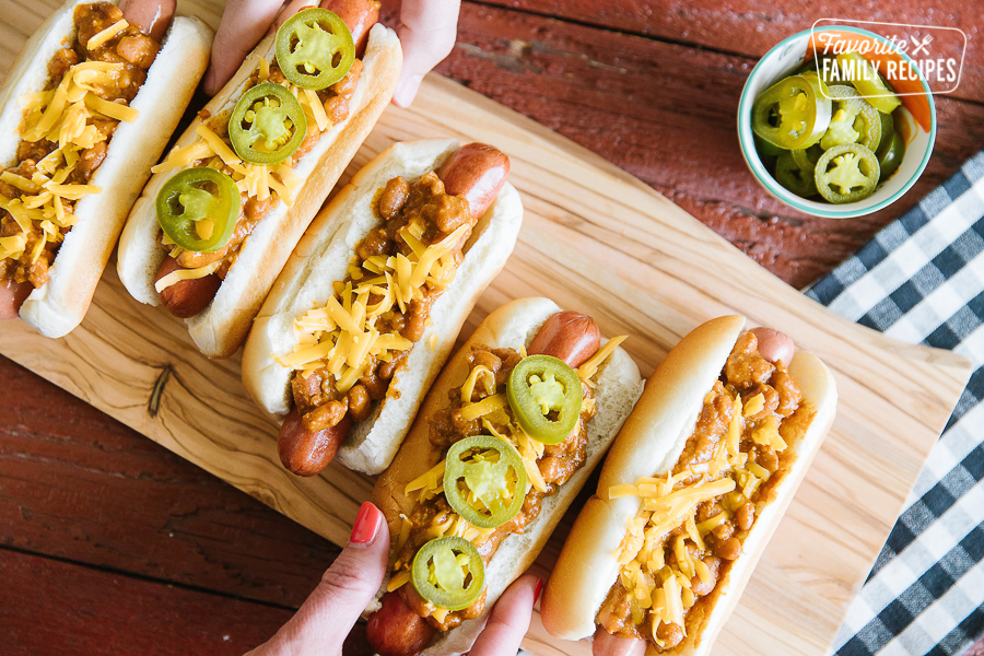 Four Chili Cheese Dogs on a tray with a cup of sliced jalapeños on the side