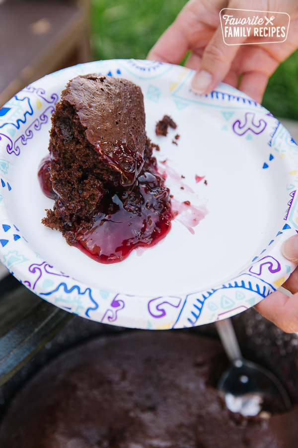 A slice of chocolate raspberry cake served from a Dutch oven onto a paper plate