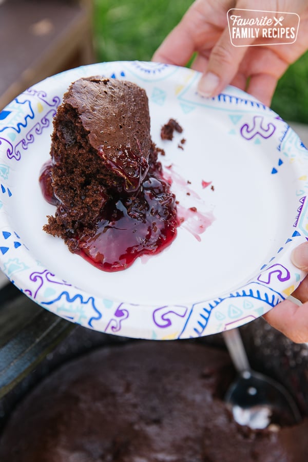 A slice of chocolate raspberry cake served from a Dutch oven onto a paper plate