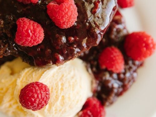 A serving of Chocolate Raspberry Cake with ice cream and raspberries as a garnish