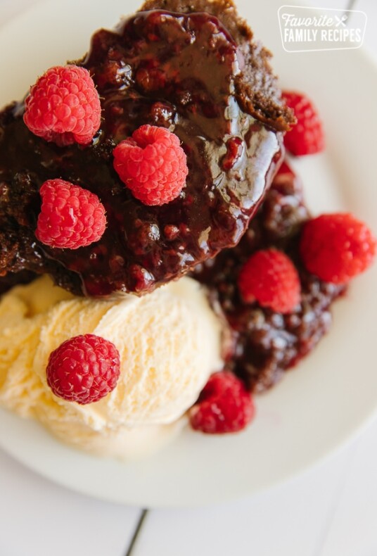 A serving of Chocolate Raspberry Cake with ice cream and raspberries as a garnish