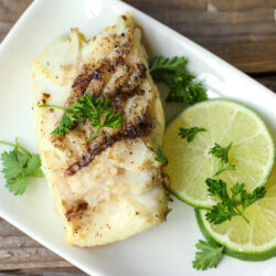 Cilantro Lime Grilled Halibut on a plate with lime slices and cilantro garnish on a plate