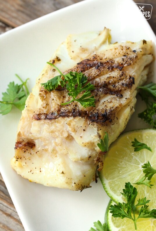 Grilled Cilantro Lime Halibut on a plate garnished with lime slices and cilantro