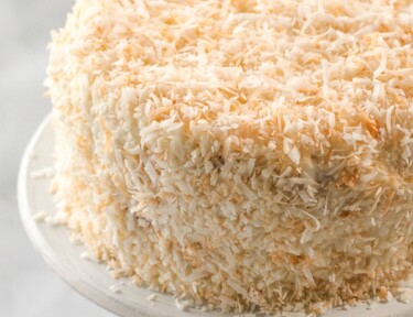 A round coconut cream cake on a cake platter