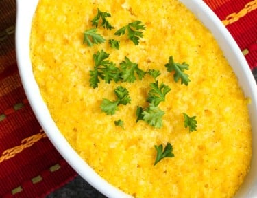 A casserole dish of Sweet Corn Cake (Tamalitos) on a brightly colored placemat