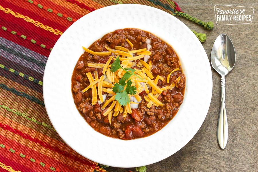 Chili in a white bowl with a spoon on the side. 