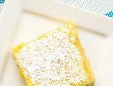 A square white plate with a lemon bar on it