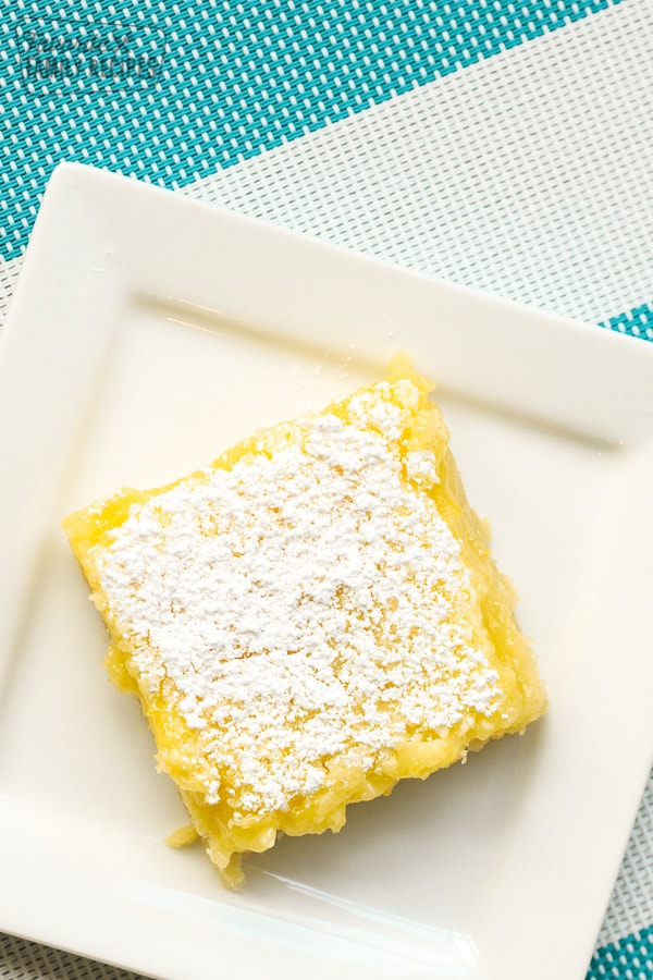 A square white plate with a lemon bar on it
