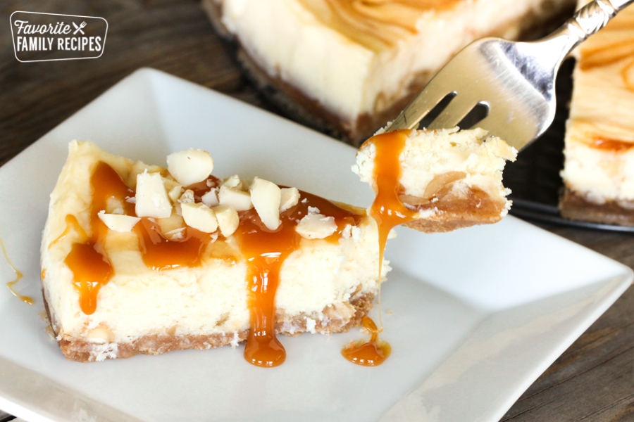 A piece of White Chocolate Cheesecake with caramel and academia nuts on top