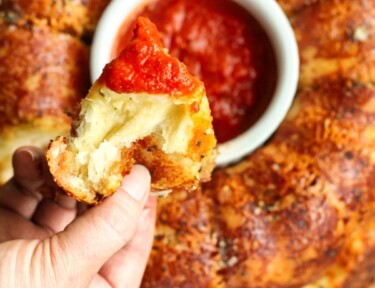 Parmesan pull apart bread being dipped in marinara sauce